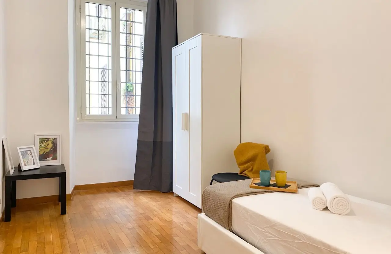 Prima camera singola con letto e arredi essenziali